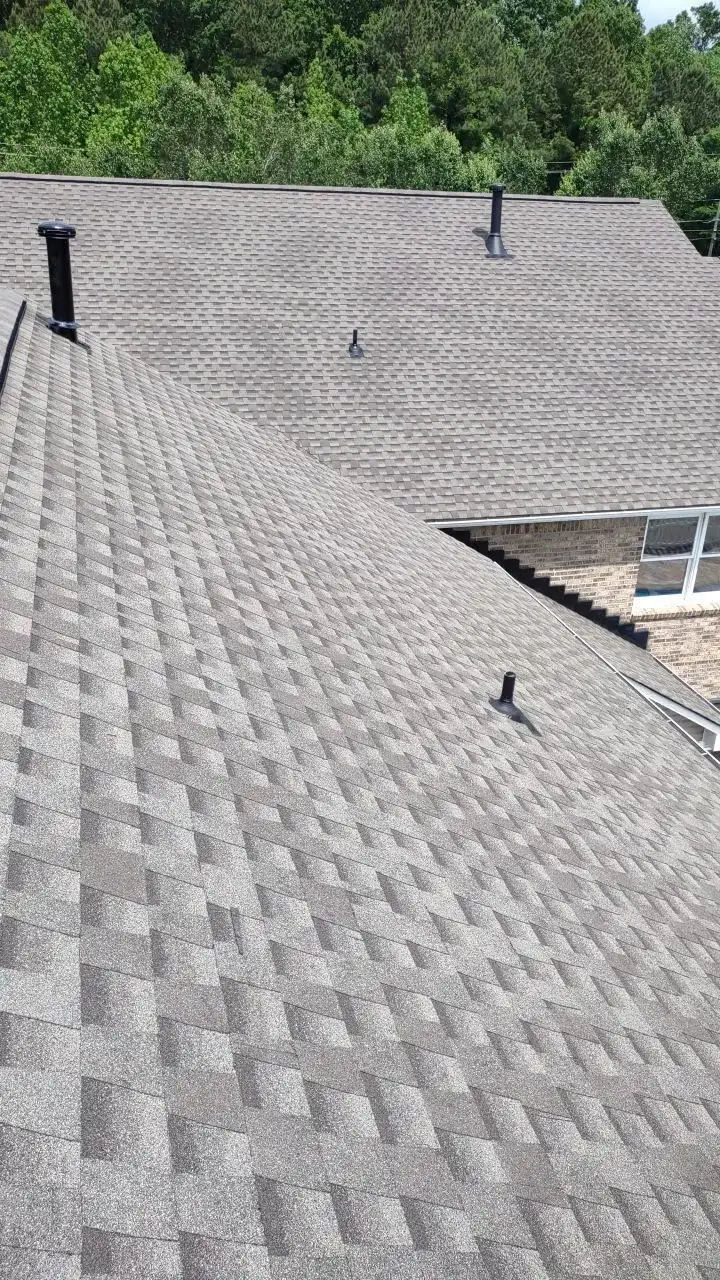 A roof with a black chimney and a brick chimney.